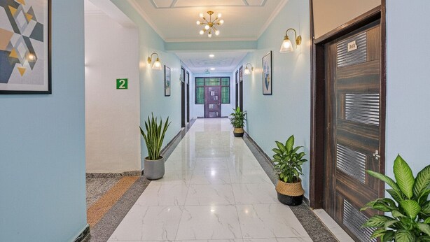 A hallway with a number 2 sign, potted plants, and a door with a number plate. - Fabhotel Akki Residency 66 (Noida)