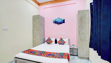 A bedroom with a bed, a pink wall, a decorative painting, and a blue curtain.