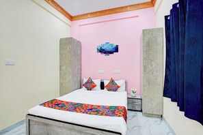A bedroom with a bed, a pink wall, a decorative painting, and a blue curtain. - Via Golden Inn I (Bengaluru)