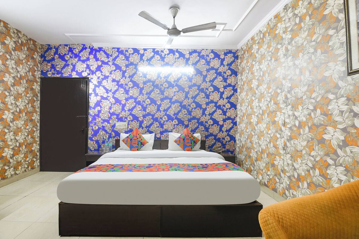 A bedroom with a bed, pillows, a ceiling fan, and floral wallpaper.