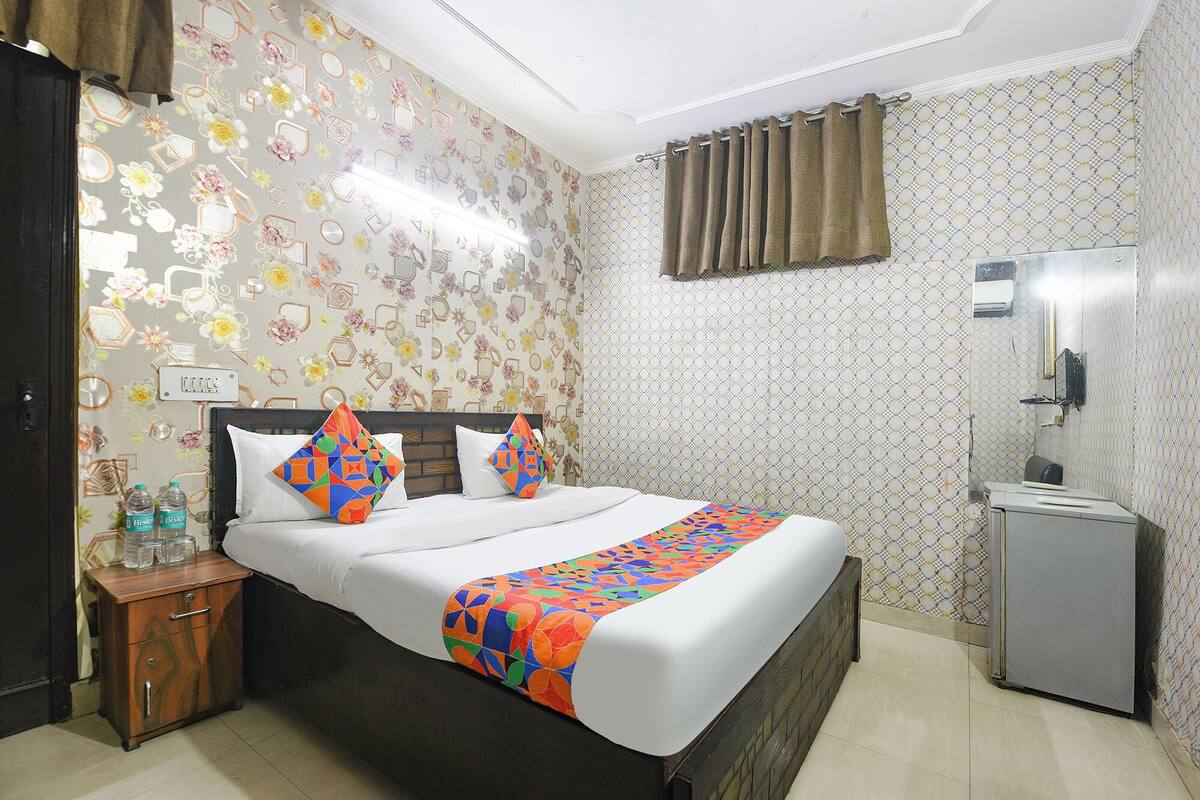 A hotel room with a bed, a nightstand, a mirror, and a wardrobe.