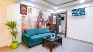 A modern living room with a teal sofa, a glass coffee table, and a Buddha mural on the wall. - Fabhotel Arsh Executive Inn (Kalyan)