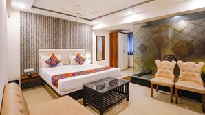 A modern hotel room with a large bed, a glass coffee table, a sofa, and a seating area with chairs. - Fabhotel Arsh Executive Inn (Kalyan)