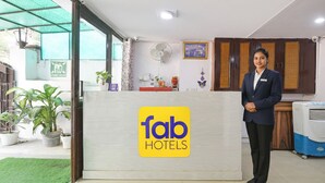 Una reception hotel con un logo, una recepcionista e una ventola.