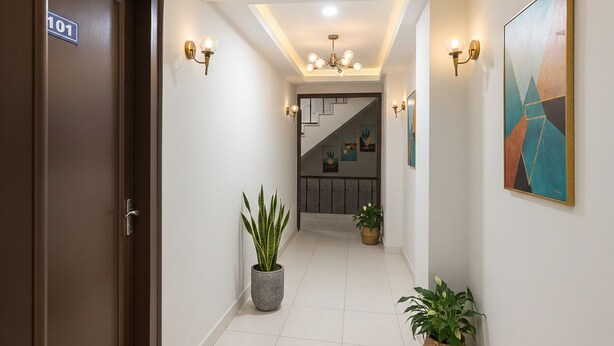 Un corridoio con una scala, piante in vaso e lampade a parete.
