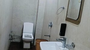A small bathroom with a toilet, a sink, and a mirror. - Fabhotel Red Pepper (Faridabad)