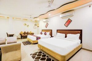 A hotel room with two beds, a sofa, a chair, and a ceiling fan. - Fabhotel Suncity (Penumuluru)