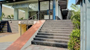 Un escalier en pierre menant à l’entrée d’un bâtiment, avec un panneau indiquant « PARKING ».