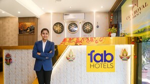 Un comptoir d’accueil avec une enseigne indiquant « fab hotels » et un mur décoratif orné d’horloges portant les inscriptions « Dubaï », « Shanghai » et « Kolkata ».