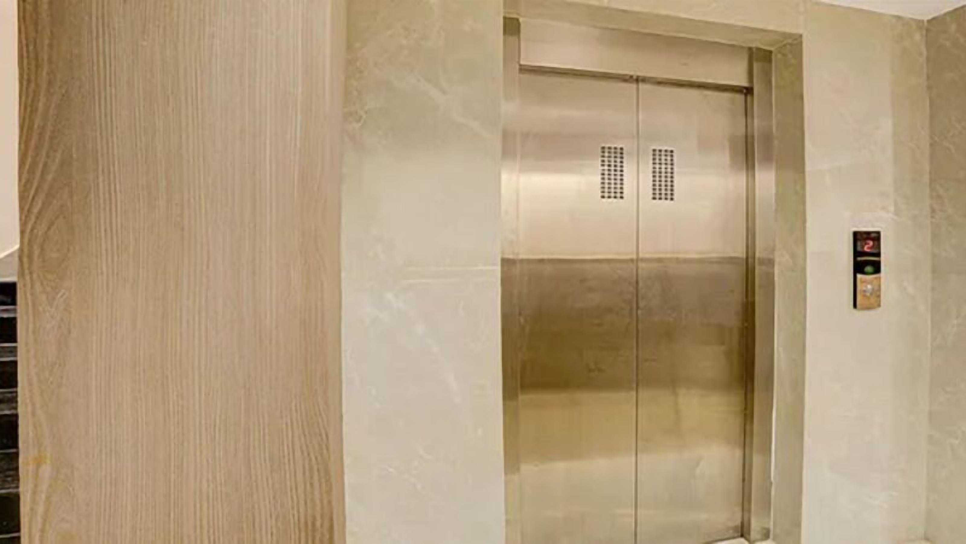 An elevator with a metallic finish and a control panel with a digital display.