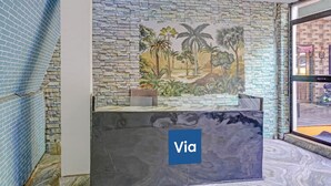 A room with a stone wall mural, a Via sign, and a view through a window. - Via Simba resort - 200m From Arambol Beach (Arambol)