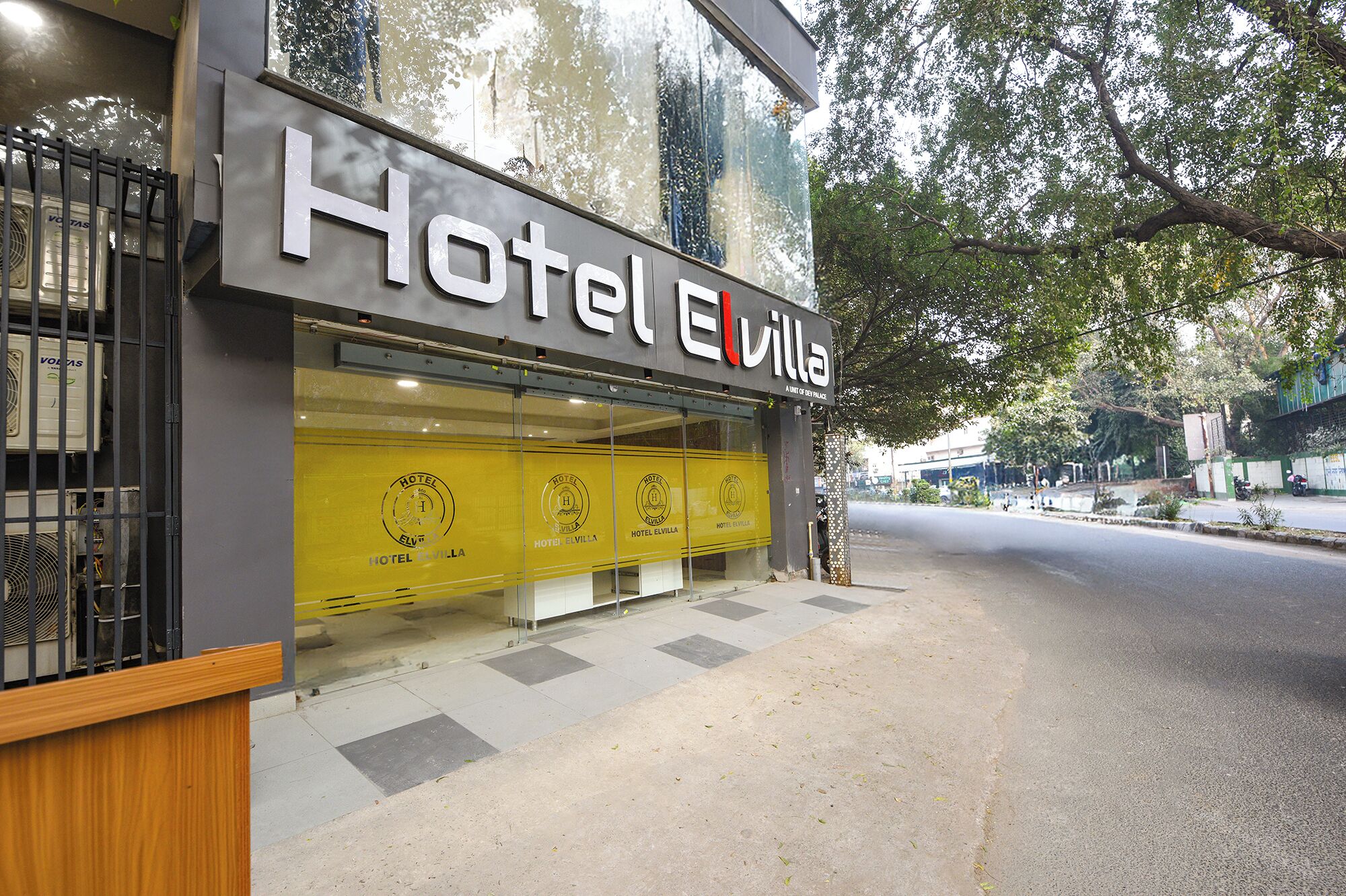Un hotel con fachada moderna, entrada visible y una vista despejada de la calle al fondo.