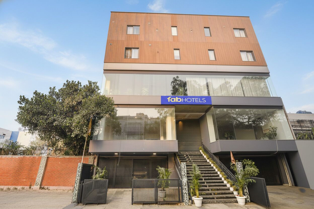 Un edificio moderno con un letrero de 'fabHOTELS', que cuenta con una escalera, una entrada protegida por una reja y plantas en macetas.