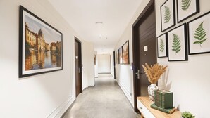 A hallway with framed artwork, a wooden bench, and a vase with dried plants. - FabHotel Prime Elvilla I-@ Rajouri Garden, Delhi (New Delhi)