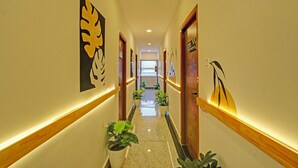 A hotel hallway with a polished floor, wooden doors, and wall-mounted artwork. - Fabhotel Casa Grand Himayathnagar (Hyderabad)