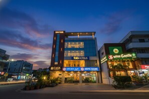 Un hôtel moderne doté d’une façade imposante, avec une entrée bien visible, une enseigne indiquant « fabHOTELS » et une autre indiquant « HDFC BANK ».