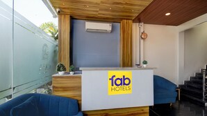 Ein Empfangsschalter mit einem 'fab hotels' Schild, einer Uhr und einer Treppe, die in einen anderen Bereich führt.