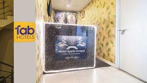 A hotel entrance with a check-in/out time sign, a decorative wall, and a door. - FabHotel Apple - Nr. by ITI (Indore)