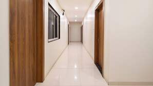 A corridor with wooden doors and a tiled floor. - FabHotel Apple - Nr. by ITI (Indore)