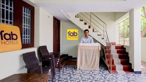 A hotel reception area with a desk, chairs, a staircase, and a sign for 'fab hotels'. - FabHotel Dream Inn - Mogappair East (Chennai)