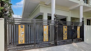 A gated entrance with decorative panels and a modern building in the background. - FabHotel Dream Inn - Mogappair East (Chennai)