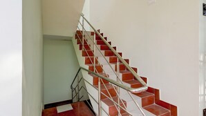 A staircase with red and white tiles, metal handrails, and a white wall. - FabHotel Dream Inn - Mogappair East (Chennai)