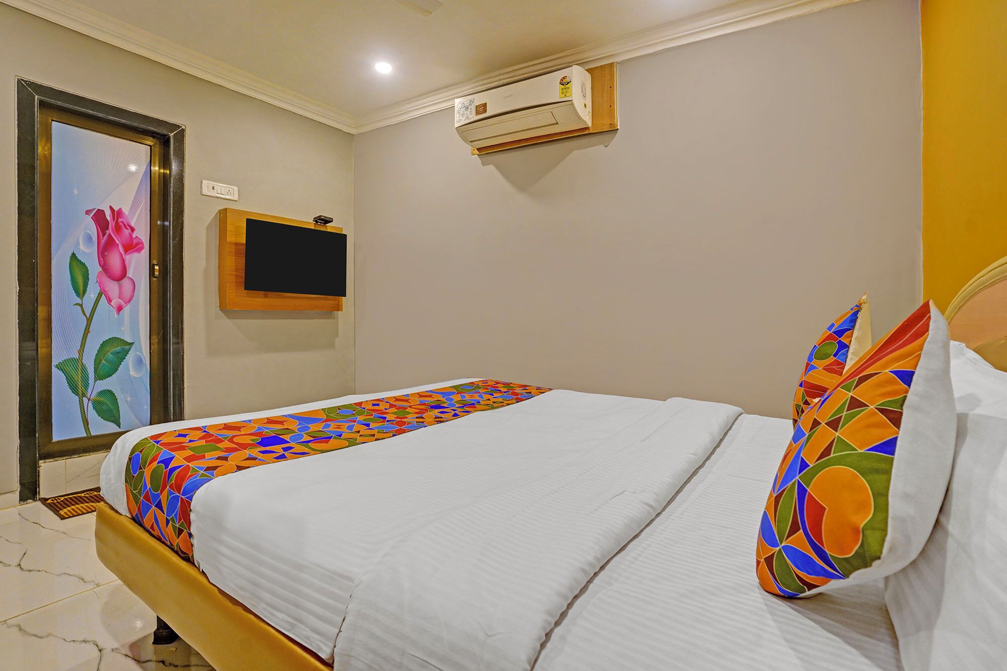 Una habitación de hotel con una cama, un televisor montado en la pared y un equipo de aire acondicionado.
