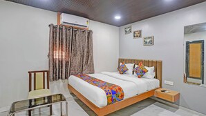 A bedroom with a bed, a chair, an air conditioner, and a nightstand. - Fabhotel Stay Land Plus (Mumbai)