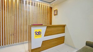 A hotel reception desk with a wooden finish and a sign reading "tab hotels". - Fabhotel Stay Land Plus (Mumbai)