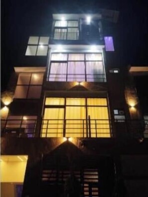 A multi-story building with illuminated windows and a prominent central entrance. - Fabhotel Karshani Kripa Dham (Vrindavan)