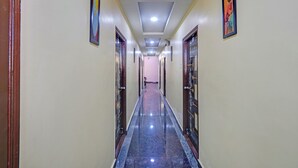 A long, narrow hallway with a marble floor, flanked by doors on both sides, leading to a room at the end. - Via Nobel Grand (Hyderabad)