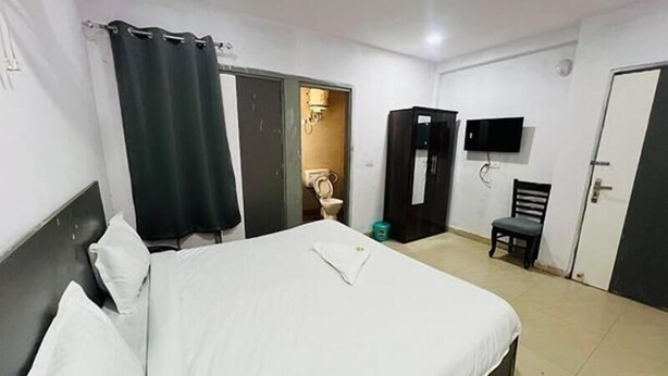 Ein Hotelzimmer mit Bett, Sessel, Fernseher und Kleiderschrank.