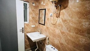 Ein Badezimmer mit Marmorwand, einem Waschbecken, einem Spiegel und einer Dusche mit mehreren Brauseköpfen.