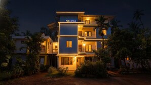 Un hôtel à plusieurs étages au design moderne, doté de balcons et d’une entrée bien éclairée.