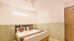 Une chambre d’hôtel avec un lit, un ventilateur de plafond et une porte en bois.