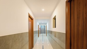 Un couloir avec des portes en bois, un sol carrelé et un miroir au mur.