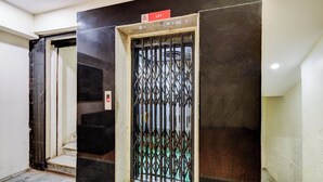 Entrada de un hotel con una puerta de metal y un cartel de ascensor encima.