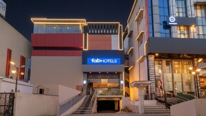 Un hotel moderno con un llamativo letrero de 'fabHOTELS', una escalera que conduce a la entrada y un camino de acceso con portones.