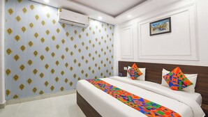 Quarto de hotel com cama, mesa de cabeceira, ar condicionado fixado na parede e um quadro emoldurado.