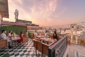 A rooftop restaurant with checkered flooring, outdoor seating, and string lights. - Fabhotel Khandaka Mahal (Jaipur)