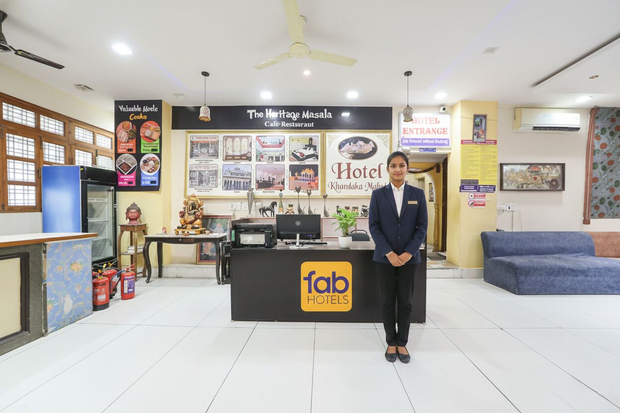 A hotel reception area with a reception desk, a sign for 'The Heritage Masala Cafe-Restaurant', and a 'fab hotels' logo.