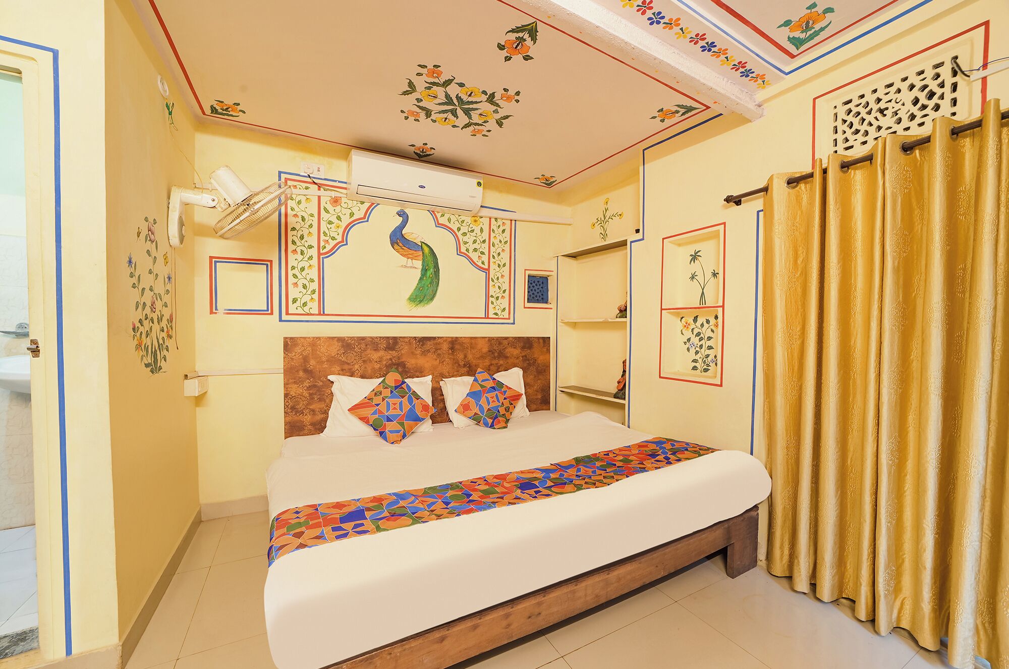 A hotel room with a bed, decorative ceiling, and curtains.