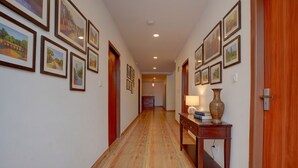A hallway with wooden flooring, framed pictures on the walls, and a table with a lamp and vase. - Fabhotel Sri Udupi Park (Bengaluru)
