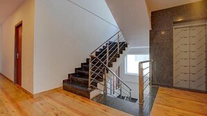 A modern interior with a wooden floor, a staircase with metal railings, and a wardrobe with a geometric pattern. - Fabhotel Sri Udupi Park (Bengaluru)