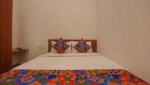 A bed with a geometric patterned bedspread, a wooden headboard, and two decorative pillows. - Fabhotel Sri Udupi Park (Bengaluru)