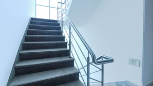 Una escalera con barandillas metálicas que lleva a un rellano con una ventana.
