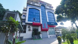 Un hotel con un letrero llamativo que dice 'Hotel Mansarovar Palace', con un estilo arquitectónico moderno, grandes ventanales y techo plano.