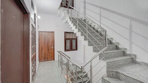 A modern interior with a staircase, a wooden door, and a window. - Fabhotel Tree View Residency (Lucknow)