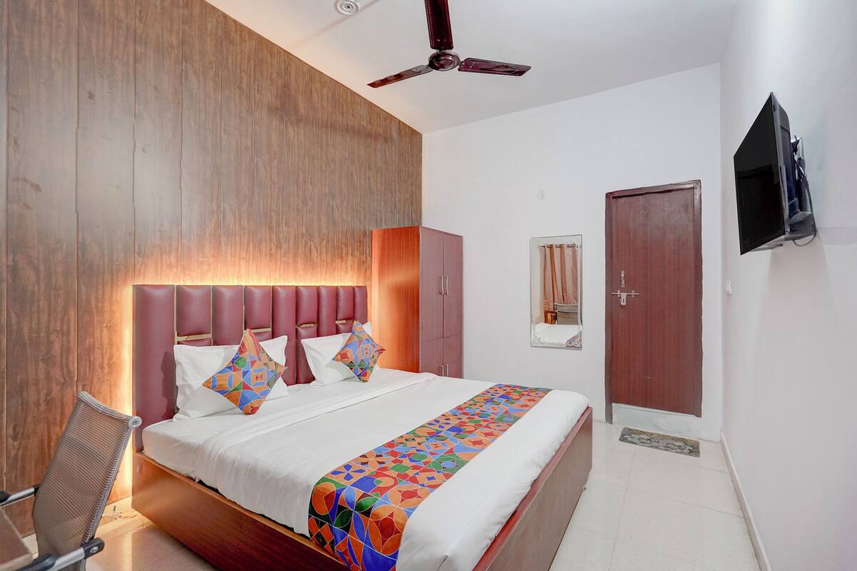 A hotel room with a bed, a chair, a wardrobe, a television, and a door.