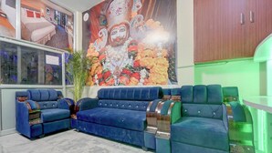 A modern living room with a blue sofa set, a green accent chair, a large decorative wall mural, and a green ambient light. - Fabhotel Tree View Residency (Lucknow)